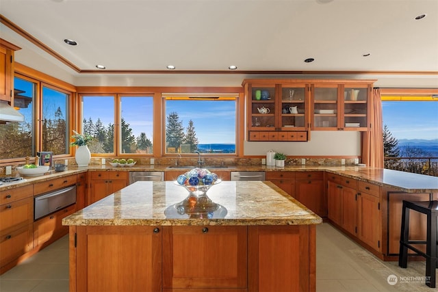 kitchen featuring sink, a breakfast bar area, appliances with stainless steel finishes, light stone countertops, and a kitchen island