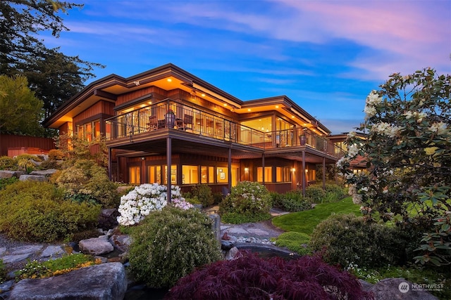 back house at dusk with a balcony