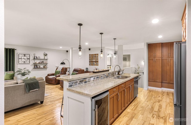 kitchen featuring light hardwood / wood-style flooring, appliances with stainless steel finishes, hanging light fixtures, a kitchen breakfast bar, and wine cooler