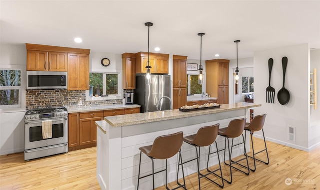 kitchen featuring a breakfast bar, a center island, pendant lighting, stainless steel appliances, and decorative backsplash