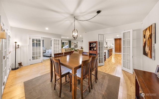 dining area featuring french doors, a notable chandelier, sink, and light wood-type flooring