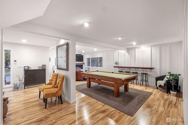 recreation room with pool table, a textured ceiling, and light wood-type flooring