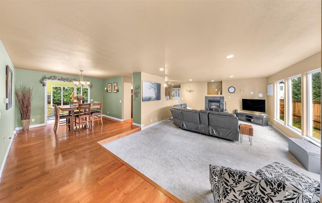 living room with an inviting chandelier, light hardwood / wood-style floors, a tile fireplace, and a wealth of natural light