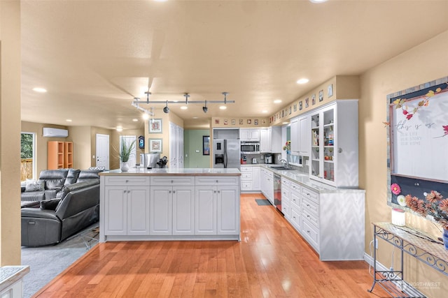 kitchen featuring sink, light hardwood / wood-style flooring, white cabinetry, a wall unit AC, and stainless steel appliances