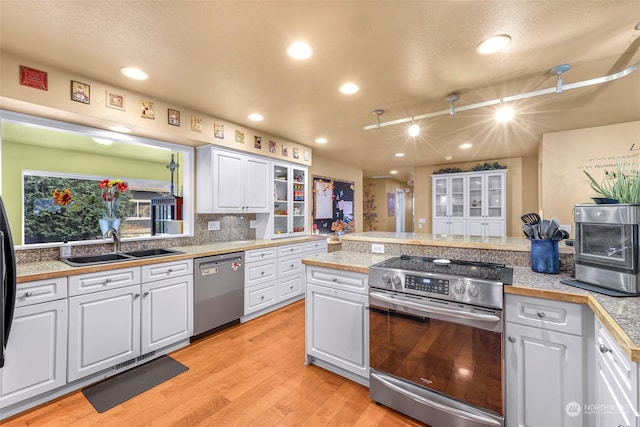 kitchen with sink, white cabinetry, tasteful backsplash, light hardwood / wood-style flooring, and appliances with stainless steel finishes