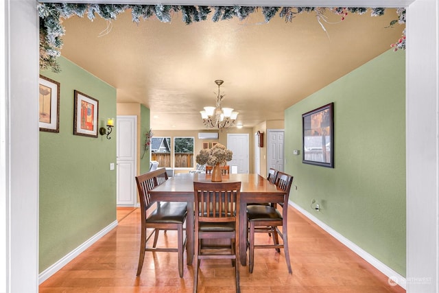 dining area featuring a wall mounted AC, a chandelier, and light hardwood / wood-style floors