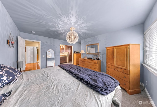 bedroom with connected bathroom and light colored carpet