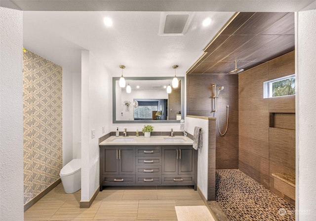 bathroom featuring vanity, tile patterned floors, toilet, and a tile shower