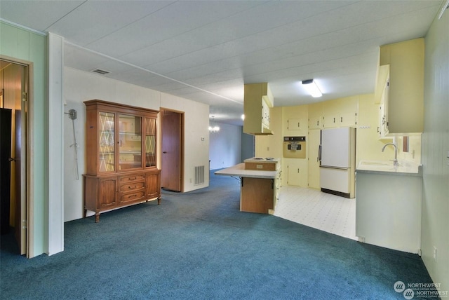 kitchen with sink, kitchen peninsula, white fridge, wall oven, and carpet