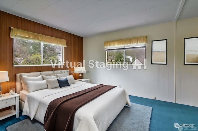 bedroom featuring multiple windows and wood walls