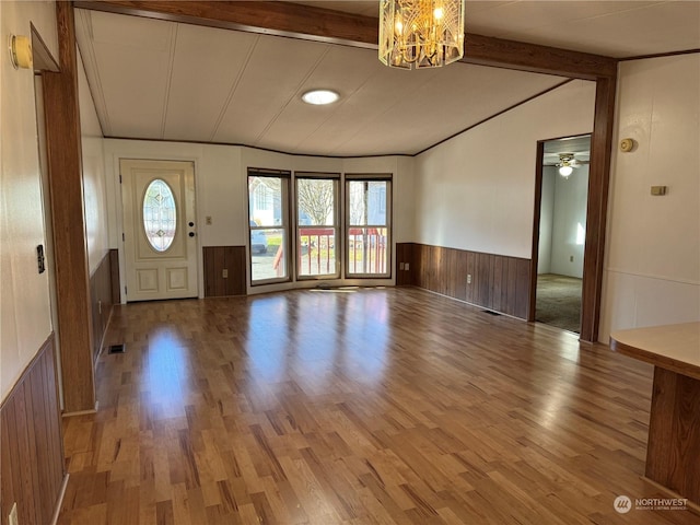 foyer entrance featuring wood-type flooring, vaulted ceiling with beams, a chandelier, and wood walls