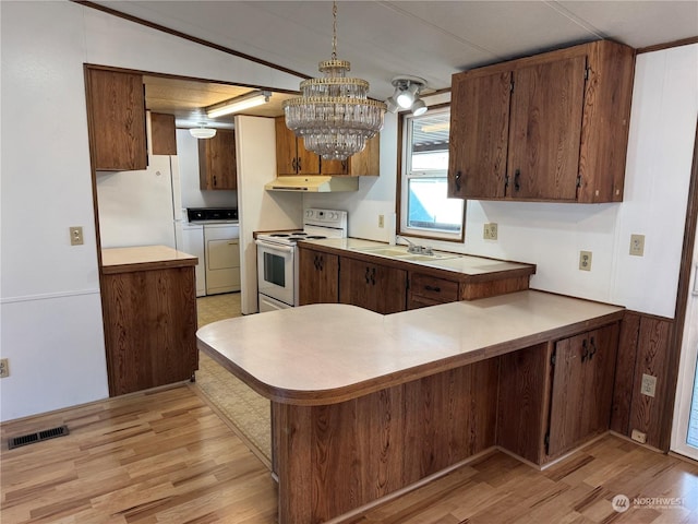 kitchen featuring white appliances, decorative light fixtures, kitchen peninsula, independent washer and dryer, and light hardwood / wood-style floors