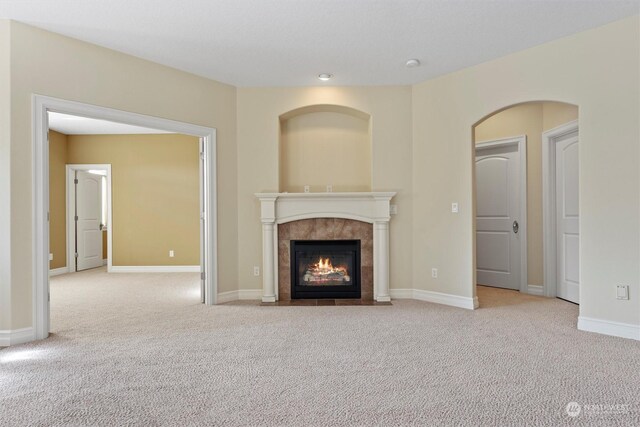 unfurnished living room featuring a tile fireplace and light carpet