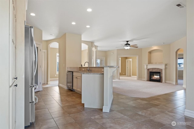 kitchen featuring stainless steel appliances, light stone countertops, plenty of natural light, and a breakfast bar area