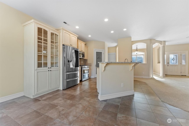 kitchen featuring a kitchen island, appliances with stainless steel finishes, carpet floors, a kitchen bar, and light stone countertops