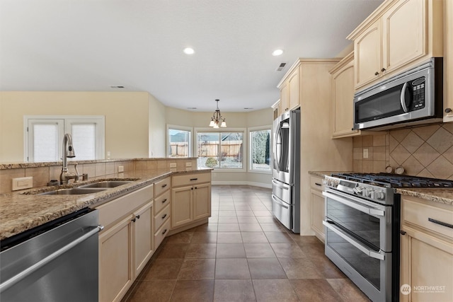 kitchen featuring pendant lighting, sink, dark tile patterned floors, backsplash, and stainless steel appliances