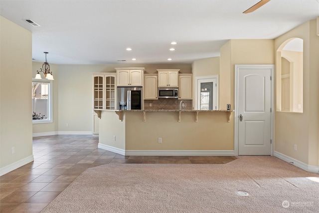 kitchen featuring stone countertops, tasteful backsplash, a kitchen breakfast bar, light tile patterned floors, and stainless steel appliances