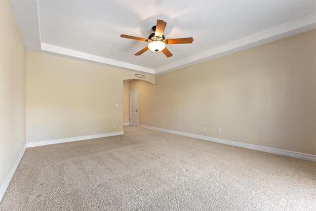 spare room with ceiling fan, a raised ceiling, and carpet