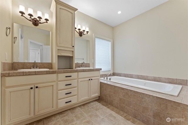 bathroom with tile patterned floors, vanity, and tiled bath