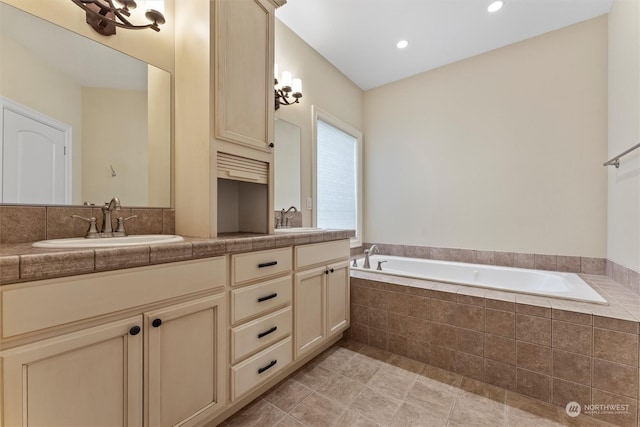 bathroom with tiled tub, vanity, and tile patterned flooring