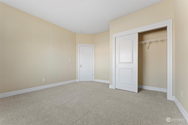 unfurnished bedroom with light colored carpet and a closet