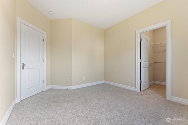 unfurnished bedroom with light carpet and a walk in closet