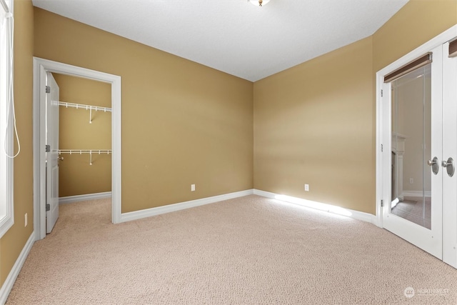 unfurnished bedroom with light carpet, a walk in closet, and a closet