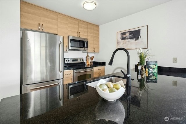 kitchen with stainless steel appliances, sink, and dark stone countertops