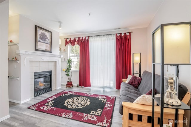 living room with a tiled fireplace and hardwood / wood-style flooring