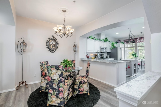 dining room with light hardwood / wood-style flooring and a notable chandelier