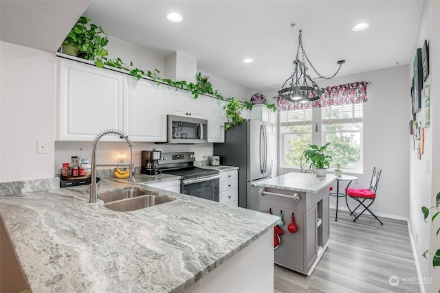 kitchen featuring sink, white cabinetry, stainless steel appliances, decorative light fixtures, and kitchen peninsula