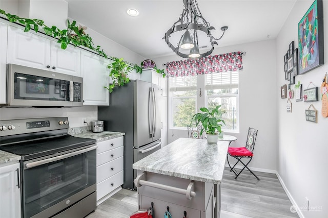 kitchen with light hardwood / wood-style flooring, hanging light fixtures, stainless steel appliances, light stone countertops, and white cabinets