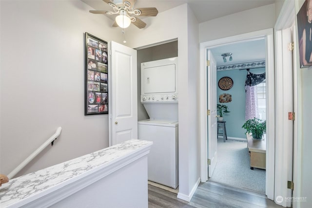 laundry room featuring stacked washer / drying machine, dark hardwood / wood-style floors, and ceiling fan