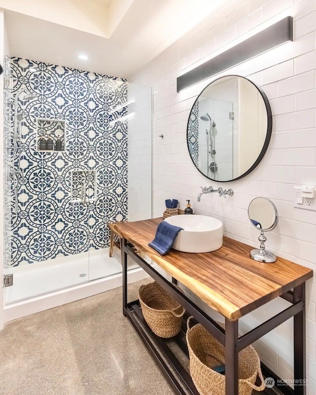 full bathroom featuring tile walls, a sink, and a shower stall