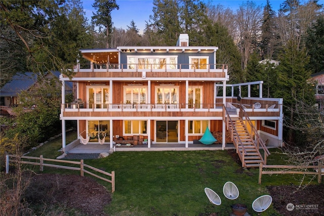 rear view of property featuring a patio, a lawn, stairway, a balcony, and a wooden deck