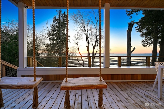 deck at dusk featuring a water view