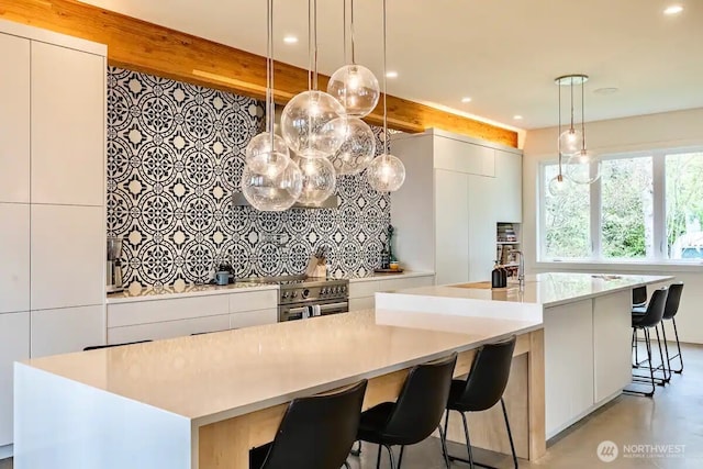 kitchen featuring high end stove, white cabinetry, light countertops, a large island, and modern cabinets