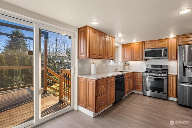 kitchen with stainless steel appliances, sink, backsplash, and light hardwood / wood-style flooring