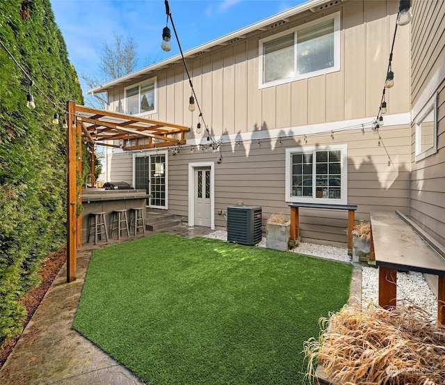 rear view of house with a bar, central AC, and a lawn