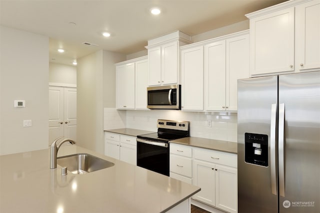 kitchen with white cabinetry, appliances with stainless steel finishes, sink, and tasteful backsplash