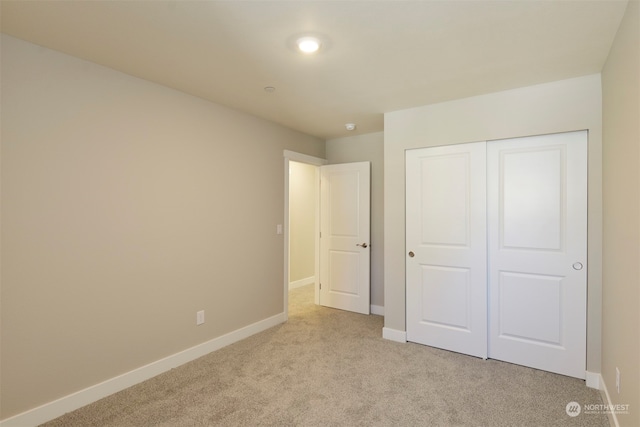 unfurnished bedroom featuring light colored carpet and a closet