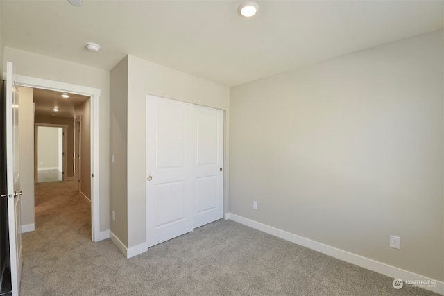 unfurnished bedroom with light carpet and a closet