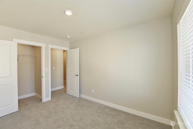 unfurnished bedroom featuring light carpet and a closet