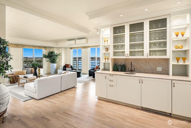 interior space with a water view, a wall mounted AC, sink, and light hardwood / wood-style flooring