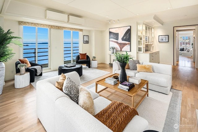 living room with a water view, a wall mounted air conditioner, and light hardwood / wood-style floors