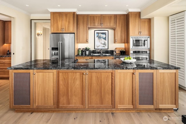 kitchen with a center island with sink, ornamental molding, dark stone counters, and appliances with stainless steel finishes