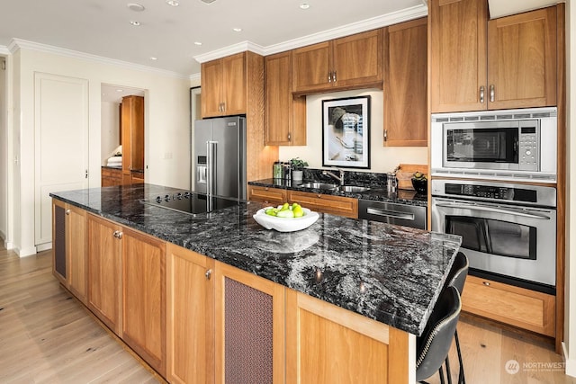 kitchen featuring dark stone counters, ornamental molding, a kitchen breakfast bar, a kitchen island, and stainless steel appliances