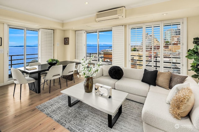 living room featuring hardwood / wood-style flooring, crown molding, a water view, a healthy amount of sunlight, and a wall unit AC