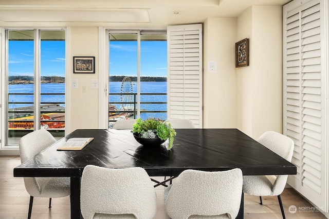 dining area with hardwood / wood-style floors and a water view