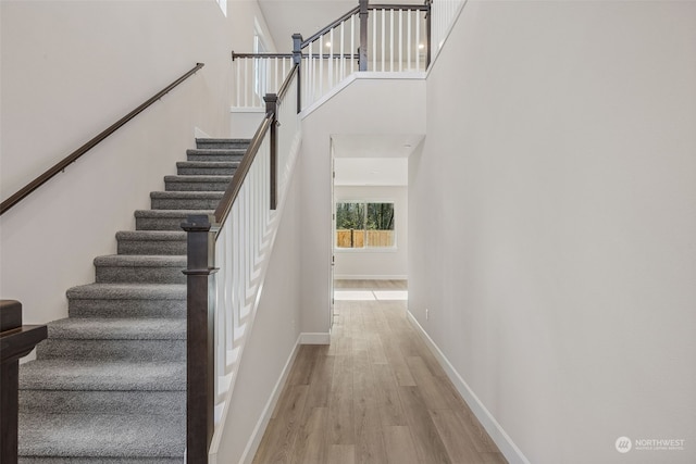 staircase with hardwood / wood-style flooring and a high ceiling